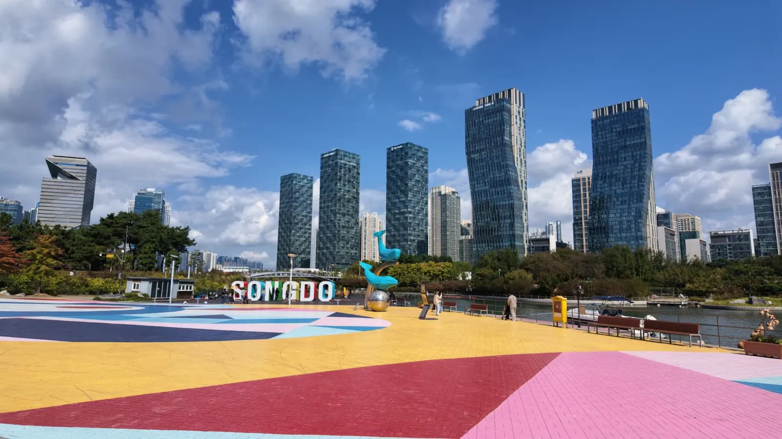 Šareni trg s natpisom Songdo i visokim zgradama pod plavim nebom