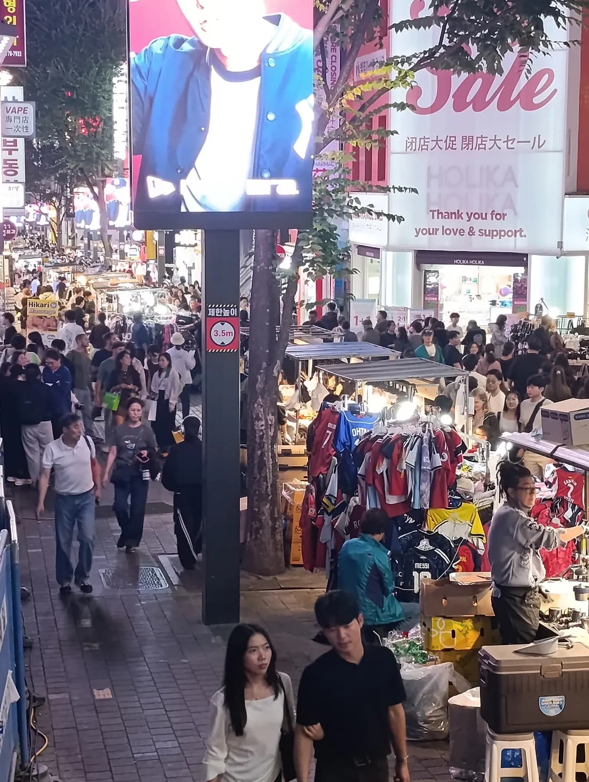 Una calle llena de gente y anuncios luminosos en Seúl por la noche